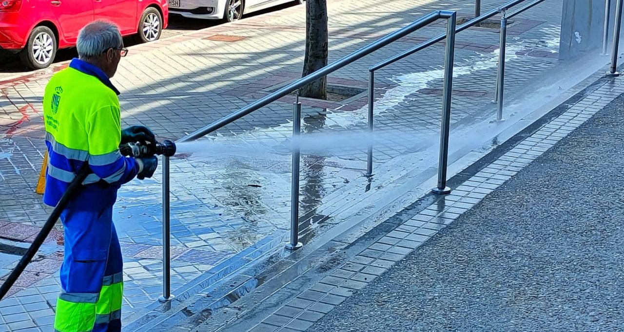 Un operario baldeando con agua una calle de Fuenlabrada