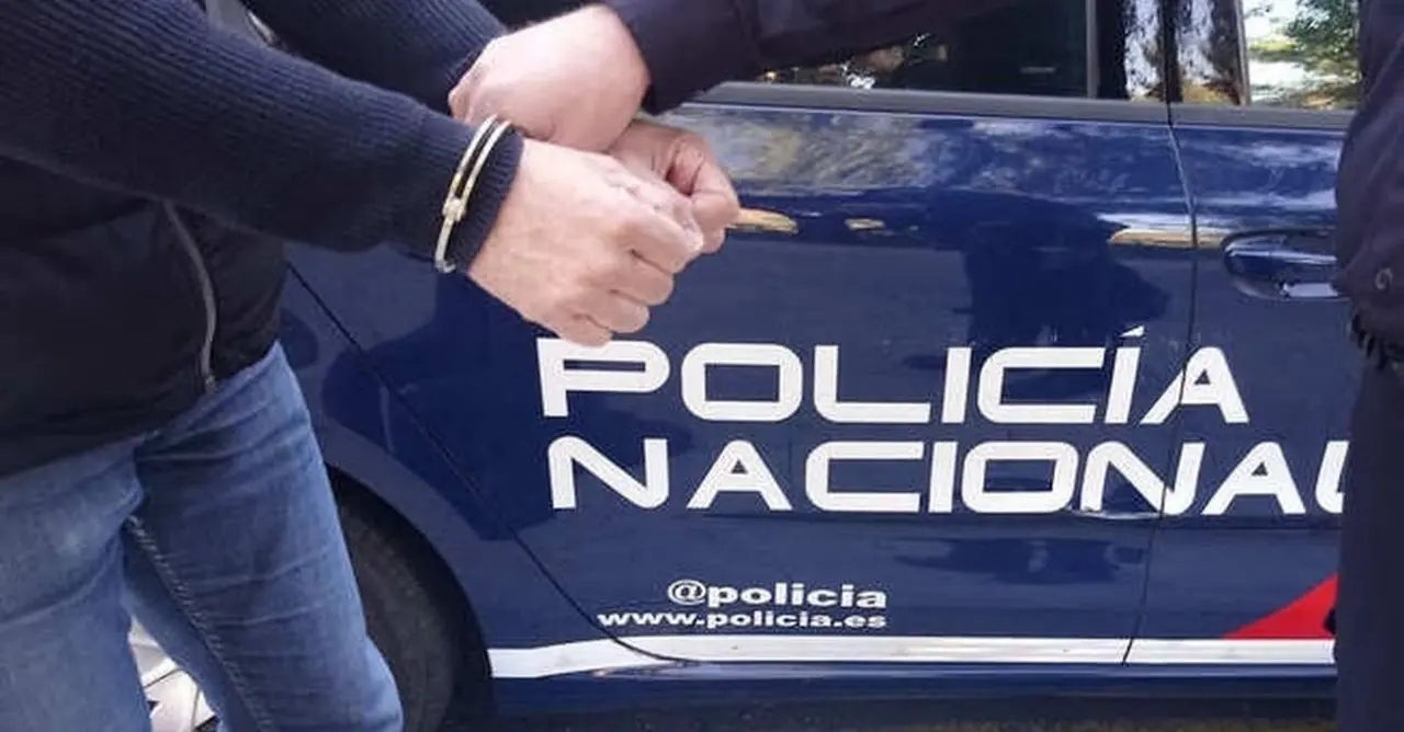 Agente esposando a un detenido junto a un coche patrulla | PN