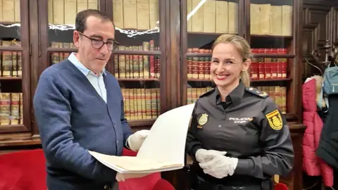 Una agente de la Polic&iacute;a Nacional entrega los documentos hist&oacute;ricos recuperados al responsable del Patrimonio del Palacio Real