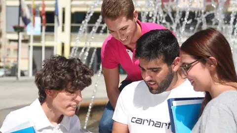 Cuatro j&oacute;venes estudiantes consultan un cuaderno en la plaza de la Constituci&oacute;n | Ayto. de Fuenlabrada